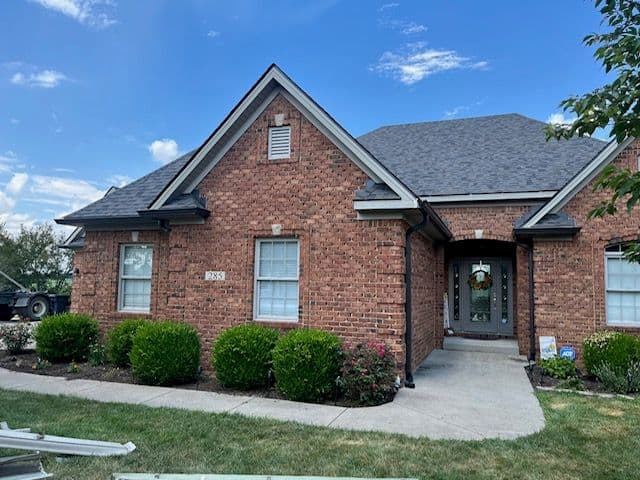 Brick suburban home with a well-maintained lawn, blue sky, and inviting front entrance.