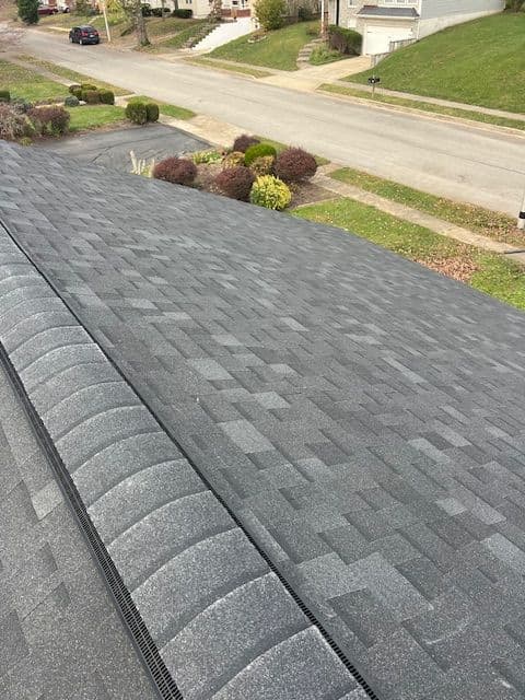 Aerial view of a gray asphalt shingle roof on a residential home with landscaped yard.