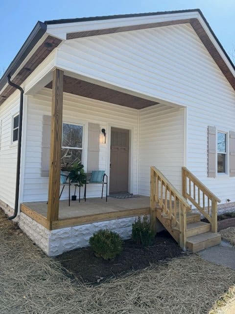 Newly renovated white house exterior with porch, steps, and decorative plants. Ideal for curb appeal.