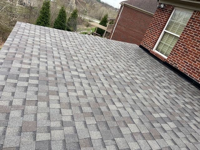 New asphalt shingle roof installation on a residential home with a scenic background.