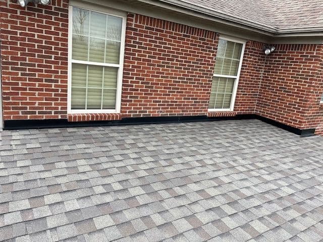 roof with gray shingles and brick wall, featuring two windows and outdoor lighting fixtures