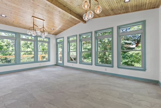 Bright, spacious living room with large windows, wood ceiling, and modern light fixtures.
