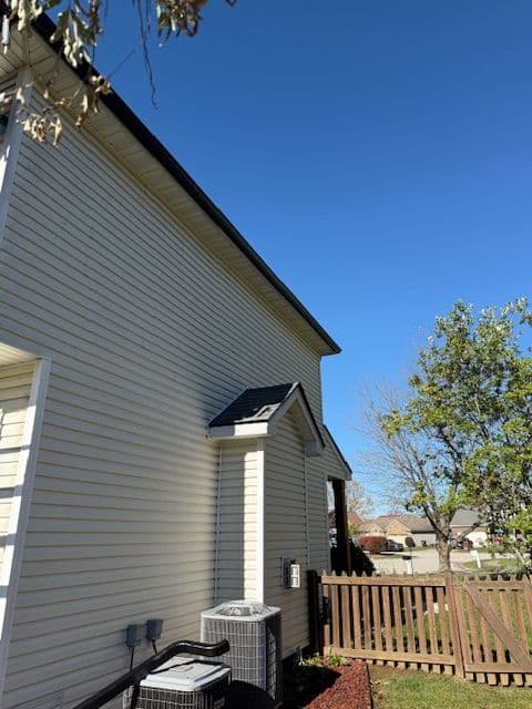 Side view of a house with a clear blue sky, HVAC unit, and a well-maintained yard.
