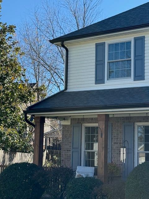 Two-story home exterior featuring gray shutters and a well-maintained yard in daylight.