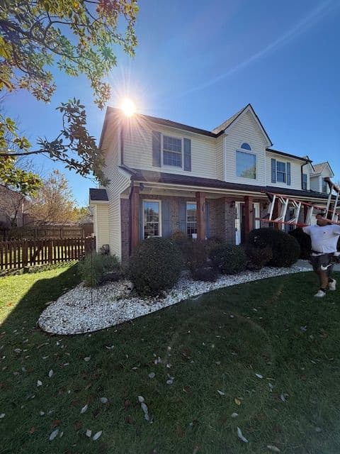 Sunlit house exterior with landscaped garden and white gravel along the foundation.