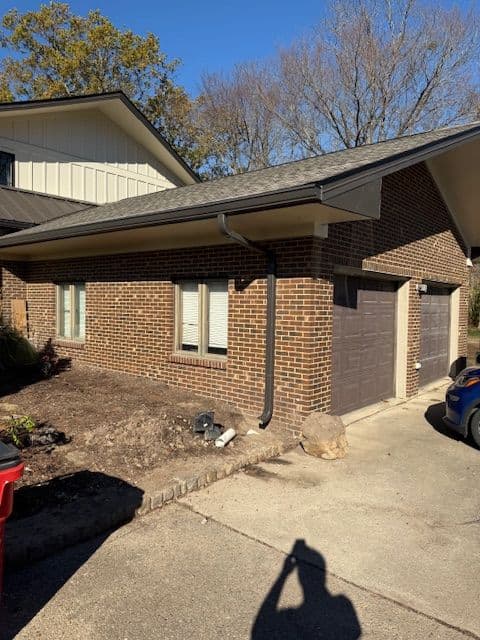 Modern brick house with a garage, clear blue sky, and well-maintained landscaping.