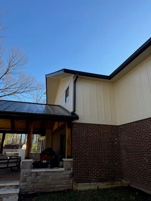 Modern home exterior featuring brick and vinyl siding under a clear blue sky.