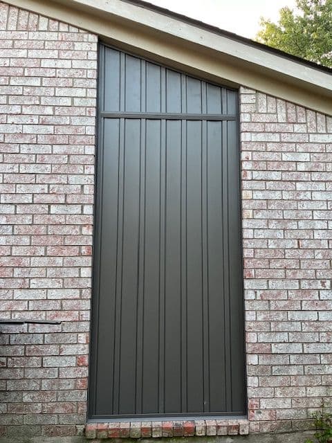 Modern vertical panel siding installation on a brick wall, enhancing home exterior design.