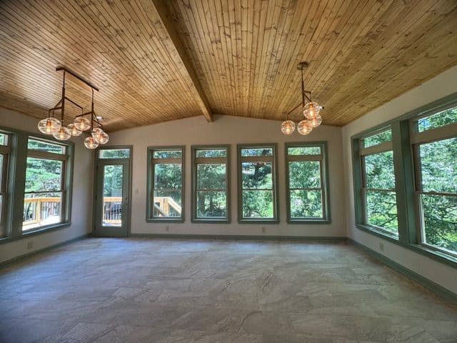 Spacious living room with wood ceiling, large windows, and modern light fixtures.