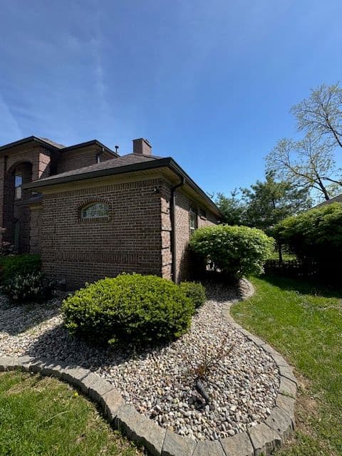 Brick house exterior with landscaped garden and clear blue sky, showcasing curb appeal.