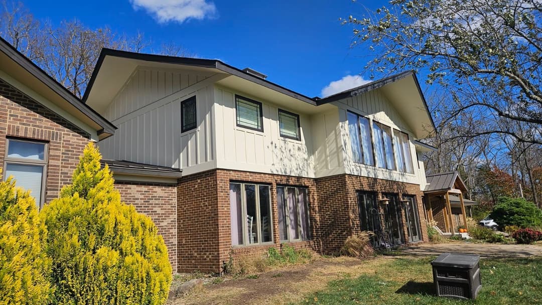 Modern two-story house with a brick exterior, large windows, and landscaped yard.