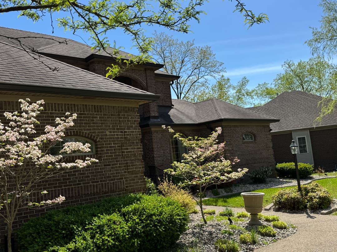 Beautiful brick house with landscaped yard, flowering trees, and clear blue sky.