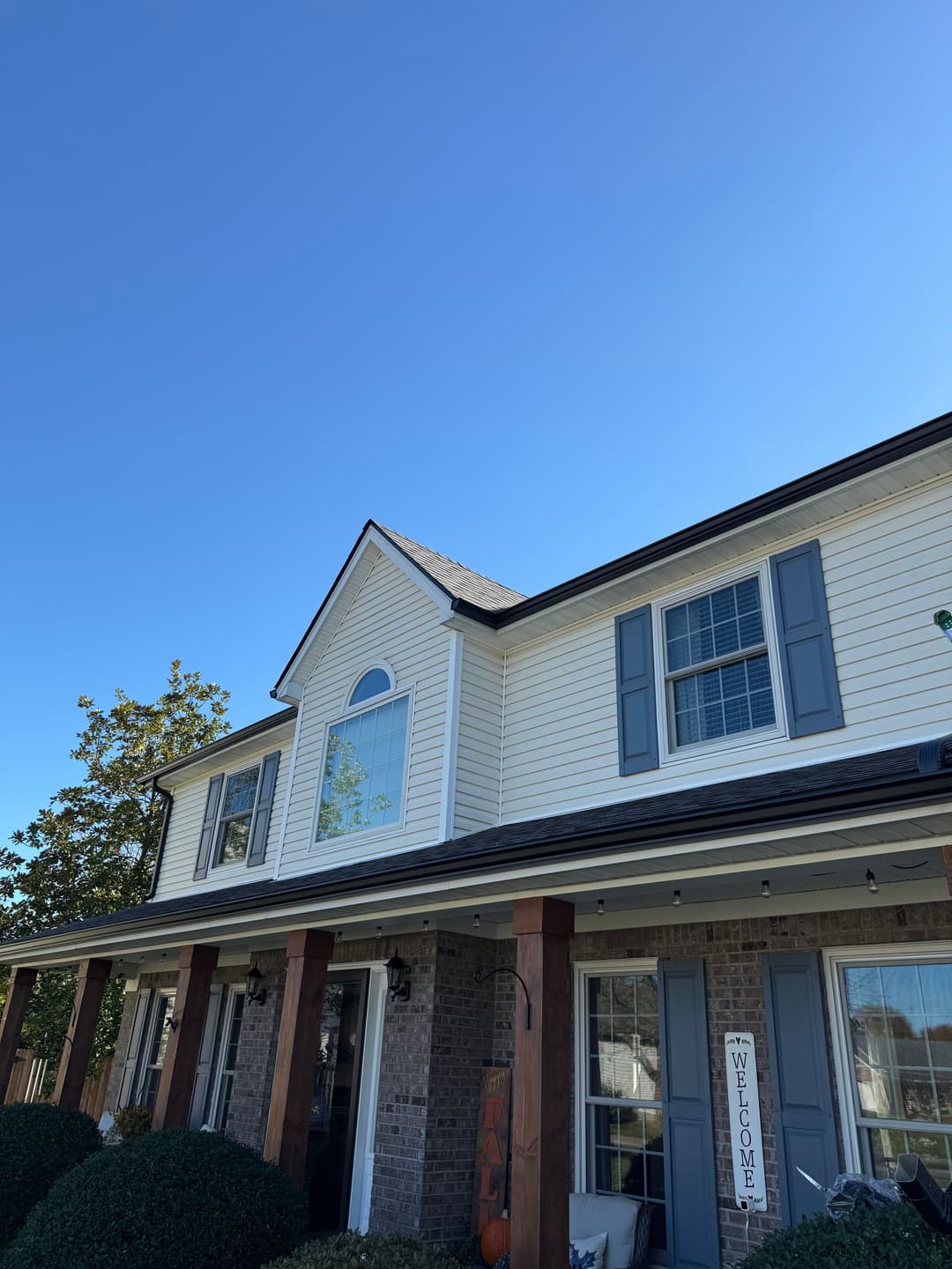 Exterior view of a two-story home with a blue sky and welcoming porch sign.