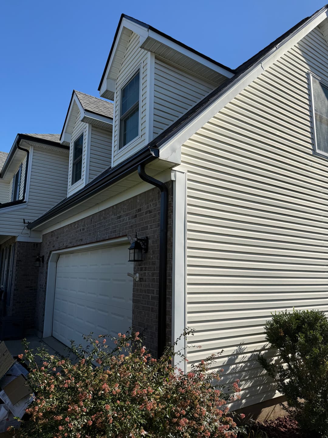 Modern house exterior featuring a brick and siding facade with garage and blue sky.