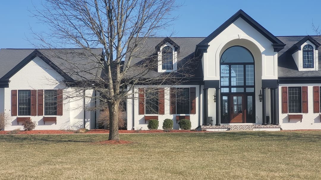 Modern white house with black accents, large front archway, and manicured lawn.