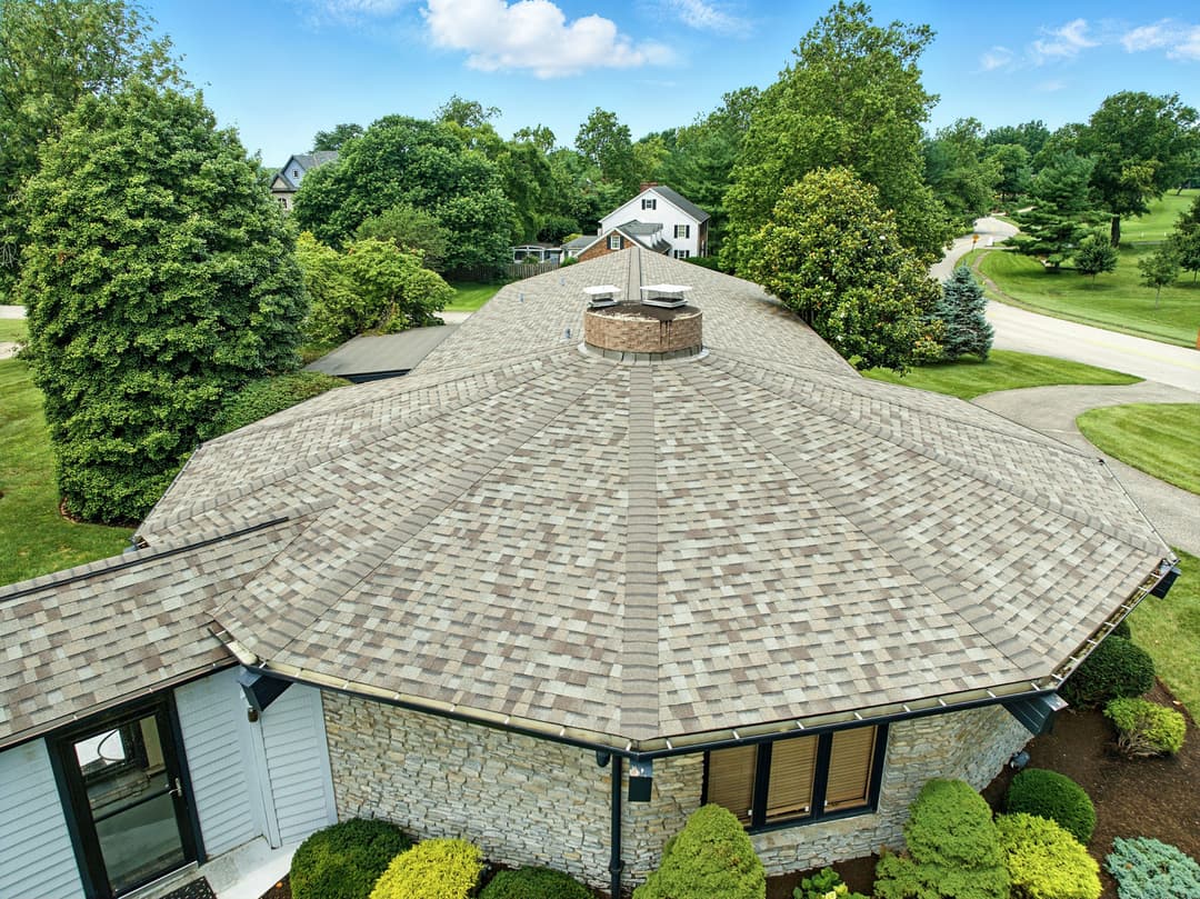 Aerial view of a modern home with a unique octagonal roof and landscaped garden.
